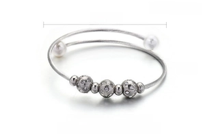 Détail du bracelet rigide torsadé en acier avec perles de coquillage et zircons