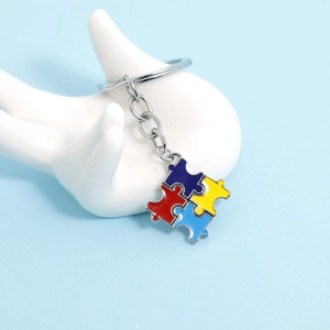 Colorful autism awareness puzzle piece keychain made of zinc alloy on a hand display