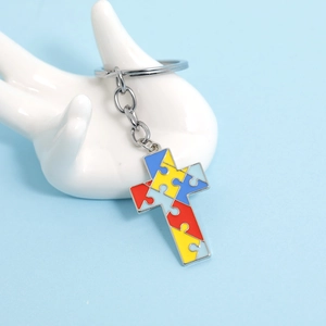 Macro shot of puzzle pattern enamel on a cross-shaped keychain held by a ceramic hand mold