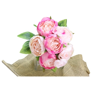 Pink artificial peony flower bouquet in glass vase on vintage newspaper backdrop