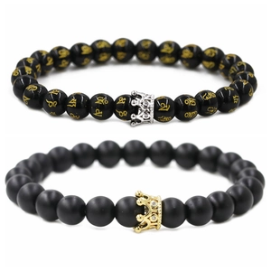 Detail of matte and polished black beads with gold crown charms on couple bracelets