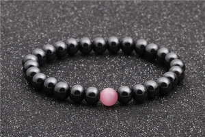 Detail of hematite beaded bracelet with a central pink cat-eye stone on black background
