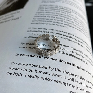 Macro shot of a 925 silver open ring with vintage floral carvings on a book page