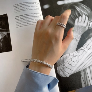 Detail of 925 sterling silver daisy ring and flower bracelet set worn by a model