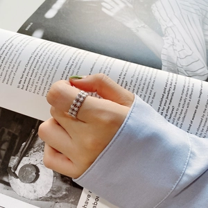 Detail view of 925 silver daisy pattern open ring on finger with fashion magazine