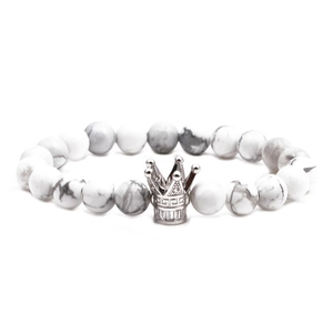 Détail macro d'un bracelet en perles de marbre blanc avec un charme couronne argenté