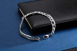 Dettaglio del bracciale a catena Figaro argento con trama a rombi su pelle nera