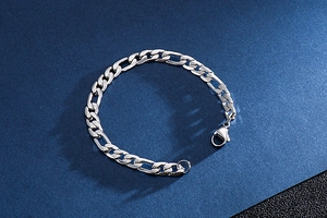 Dettaglio del bracciale Figaro d'argento con chiusura a moschettone su sfondo blu scuro
