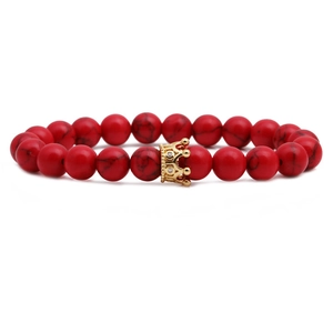 Red turquoise bead bracelet set with a detailed gold crown charm on white background