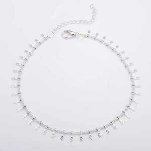 Macro detail of silver necklace featuring embossed rectangular fringe and lobster clasp