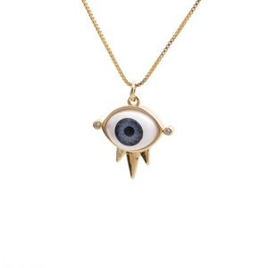 Detail of gold evil eye pendant with blue spiral pupil and spikes on snake chain