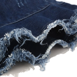 Macro detail of frayed edges and distressed denim texture on a dark blue bucket hat