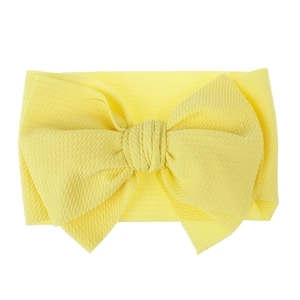 Detailed macro shot of bright yellow waffle knit fabric baby headband with large bow tie