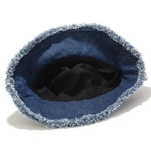 Détail d'un chapeau bob en jean bleu foncé avec bords effilochés et doublure noire