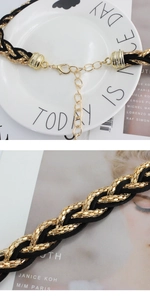 Close-up of gold metal chain woven with black fabric cord and adjustable lobster clasp closure