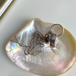 Silver layered necklace with textured pendants displayed in a natural pearl shell