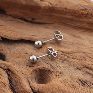 Minimalist silver spherical stud earrings with butterfly backs on natural wood surface