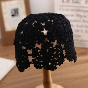 Close-up of black handmade crochet knit hat with intricate hollow floral patterns