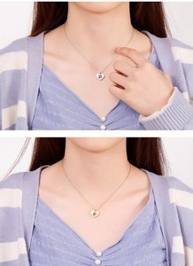 Detail of heart-shaped hollow paw print necklace in silver and gold finish worn by model