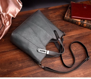 Detailaufnahme der grauen Lederhandtasche mit Metallschnalle auf Holztisch