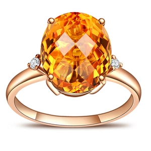 Detail of rose gold ring featuring a large oval orange gemstone and round side stones