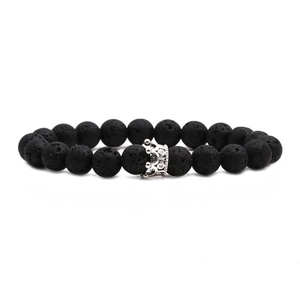 Gros plan sur les perles de lave noire et le charm couronne en argent du bracelet perlé