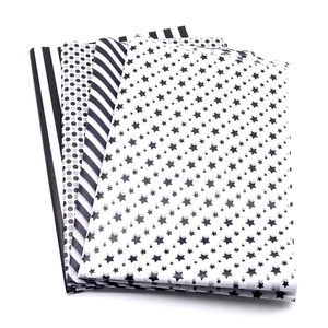 Stack of tissue paper with black star, polka dot and stripe patterns for gift wrapping