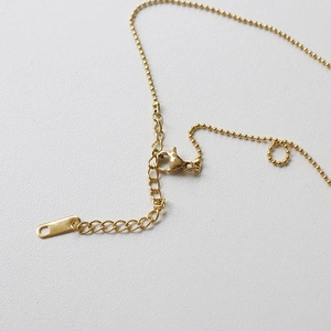Detail of golden bead chain necklace featuring a lobster clasp and extension chain