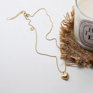 Macro shot of gold-plated 18K titanium steel heart pendant with beaded edge and ball chain