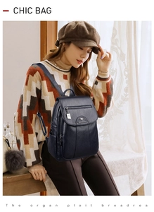 Detail view of the black leather backpack featuring golden logo and stylish metal pendant