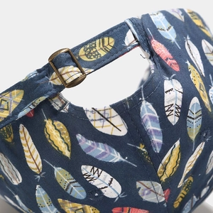 Detail of navy blue canvas baseball cap with colorful feather patterns and metal buckle