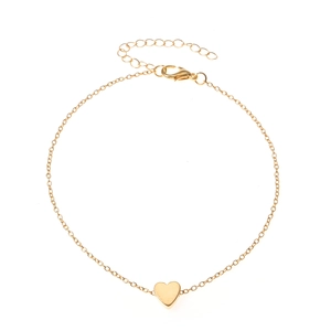 Minimalist golden bead chain anklet with a heart pendant on white background