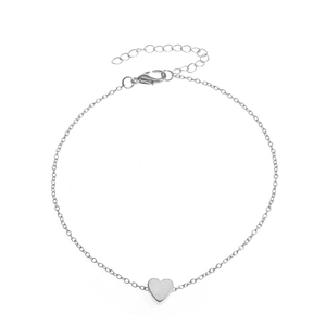 Close-up of a silver beaded anklet featuring a smooth heart pendant on white background