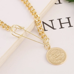 Detailed macro view of vintage gold curb chain with safety pin and coin pendant