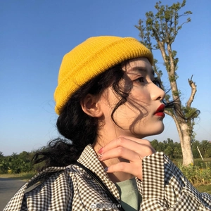 Close-up of vibrant yellow knit beanie with rolled cuff worn outdoors against blue sky