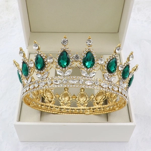 Detailed shot of golden baroque crown with green water drop rhinestones in a jewelry box