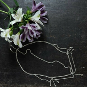 Silver rhinestone bridal hair chain with layered tassel design on a wooden background