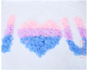 Romantic pink and purple artificial flower petals arranged in I love you shape on bed