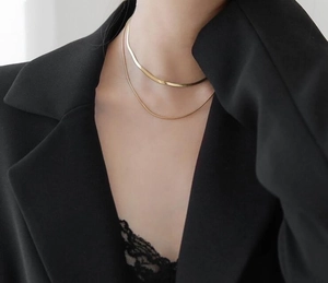 Double-layered gold-tone snake bone chain necklace on model wearing black blazer