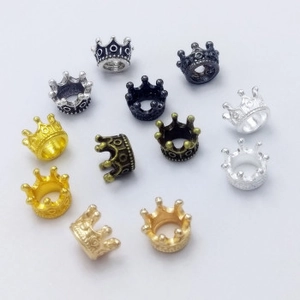 Macro view of assorted enamel crown pendants in gold, silver, and bronze for DIY jewelry