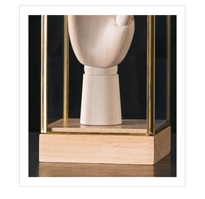 Detailed close-up of a glass display box with golden metal frame and wooden base