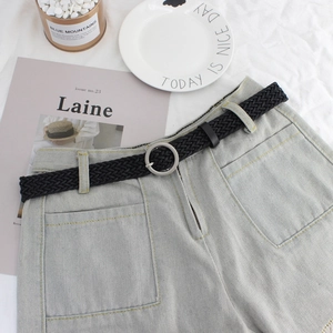 Women's black woven belt with silver round buckle on denim shorts, minimalist style