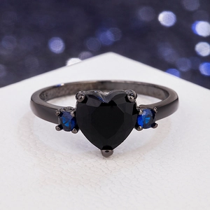Elegant black heart ring with blue side stones and 925 silver stamp on white pedestal