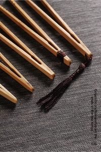 Detailed close-up of a handcrafted bamboo tea clip with elegant dark brown silk tassel