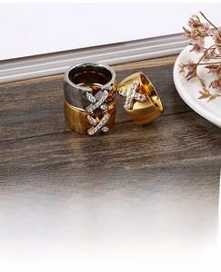 Close-up of wide band rings with crystal pavé X design on a rustic wooden surface