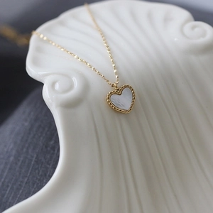Detailed macro view of heart pendant with white shell inlay and beaded gold edges