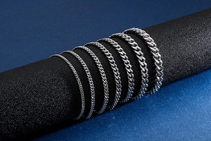 Detail view of seven silver stainless steel curb chains in various thicknesses on black display