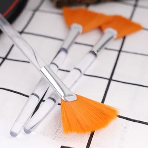 Detailed view of three fan brushes with orange bristles and transparent handles