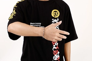Close-up of a silver rectangular link chain bracelet worn on a model's wrist