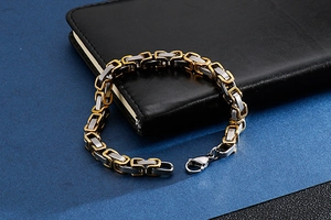Close-up of gold and silver Byzantine chain bracelet with a lobster clasp on black leather